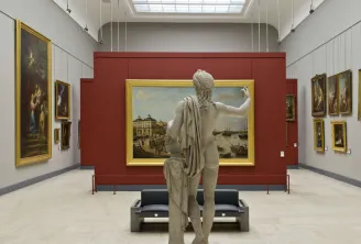 Gemäldegalerie des Kunstmuseums Bordeaux mit einer Marmorstatue im Vordergrund, die auf goldgerahmte historische Gemälde an weiß- und bordeauxroten Wänden mit Oberlichtbeleuchtung blickt.