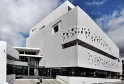 Moderne weiße Fassade des Schifffahrtsmuseums Bordeaux mit Kreislöchern, Treppen und blauem Himmel im Hintergrund