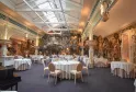 Eleganter Bankettsal im Chapon Fin in Bordeaux mit runden Tischen, goldenem Steindekor, Ziersäulen und Glasdach.