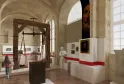 Innenraum des Nationalmuseums der Zölle in Bordeaux mit einer Ausstellung, einer historischen Holzwaage, roten Informationstafeln, Porträts und Zollobjekten in einer gewölbten Galerie.