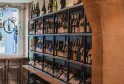 Weinregal mit schwarzen Rahmen, das zahlreiche Rot- und Weißweinflaschen in einem Bordeaux-Weinfachgeschäft oder Weinkeller enthält.